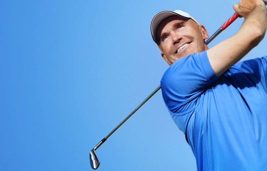 Smiling man swinging a golf club
